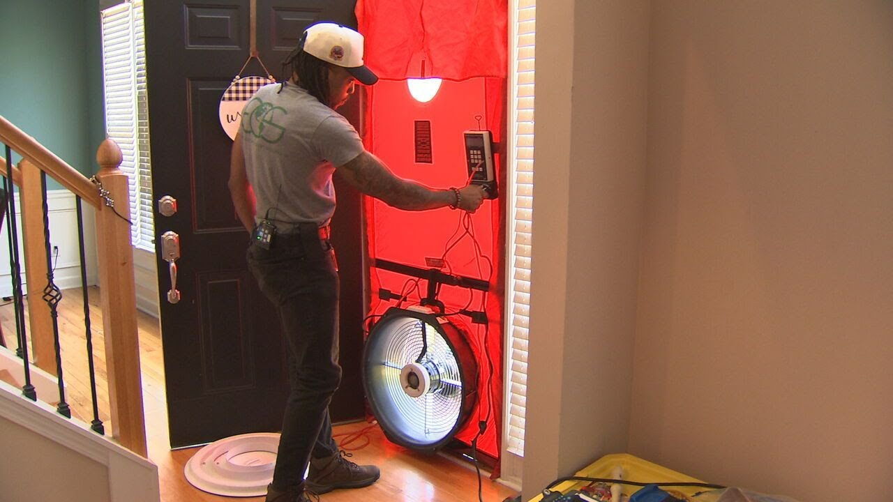 ECS technician running a blower-door test during a home energy audit, from the WSB-TV Clark Howard segment.
